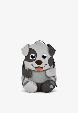 Kinder-Rucksack in Form eines lächelnden graubraunen Welpen mit großen Augen, Schlappohren und mit Reißverschluss versehene, pfotenförmige Taschen auf weißem Hintergrund.