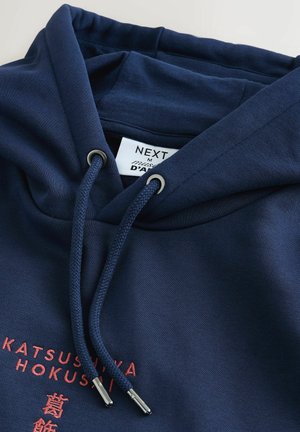 Marineblauer Kapuzenpullover mit Kordelzugkapuze. Verfügt über strukturierten Stoff, silberne Ösen und roten Text mit japanischen Schriftzeichen auf der Vorderseite.