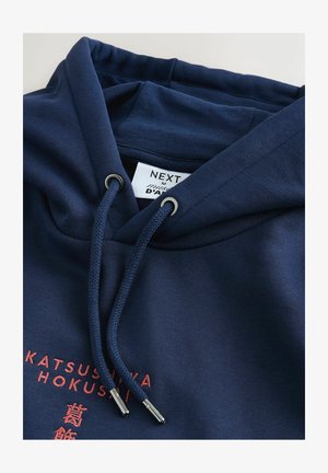Marineblauer Kapuzenpullover mit Kordelzugkapuze. Verfügt über strukturierten Stoff, silberne Ösen und roten Text mit japanischen Schriftzeichen auf der Vorderseite.