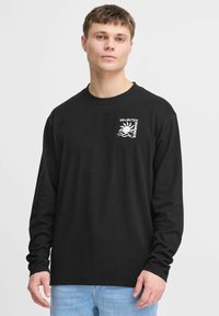 Black long-sleeve t-shirt made of cotton. Features a white graphic print of a sun and waves on the left chest area. Simple neckline and cuffs.