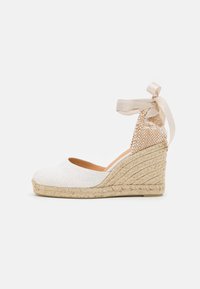 Espadrillas a zeppa in tessuto bianco con un tallone posteriore testurizzato. Presentano una base in juta intrecciata e un nastro in raso per un legaccio alla caviglia.