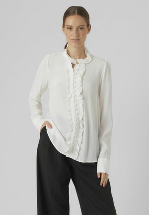 Witte blouse van lichtgewicht stof, met een gerimpelde halslijn en knoopsluiting aan de voorkant. Lange mouwen met manchet details.