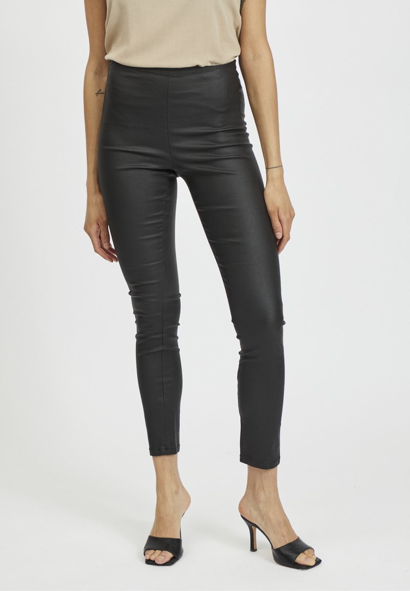 Höga svarta leggings i konstläder med en sleek, glänsande finish, som har en åtsittande silhuett och tapered design vid anklarna.