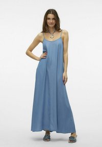 Abito lungo in denim di colore blu chiaro con spalline sottili e taglio dritto. Presenta cuciture sottili e una vestibilità informale. Accentuato da una collana circolare.