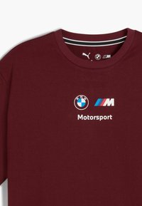 Bordeaux farvet bomulds t-shirt med rund hals. Har BMW og M-logoer sammen med ordet "Motorsport" i hvid. Korte ærmer.