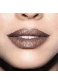 Rouge à lèvres marron mat sur des lèvres pleines avec une texture visible. Une légère brillance ajoute un effet glossy ; la peau environnante est lisse et uniforme.