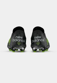 Melna un zaļa New Balance futbola apavi pāris redzami no aizmugures uz balta fona.