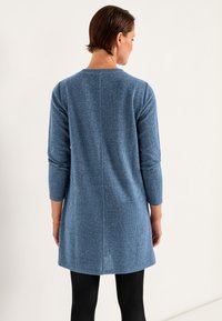 Rippstrickkleid in sanftem Blau, knielang, mit Dreiviertelärmeln und rundem Halsausschnitt. Glatte Textur, schlichtes Design, ohne sichtbare Beschläge.