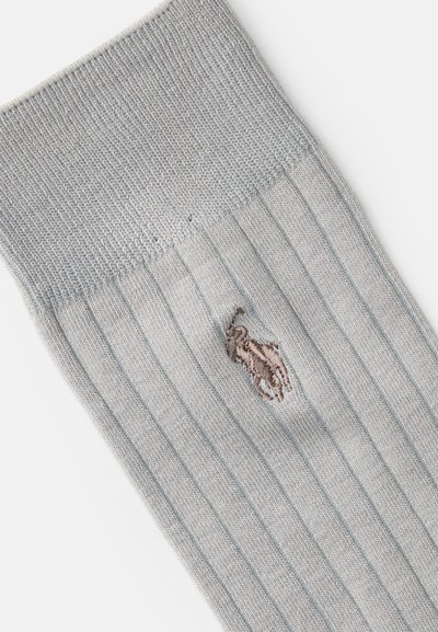 Calcetines de rayas gris claro con una textura suave, que presentan un pequeño logo bordado marrón cerca del tobillo.
