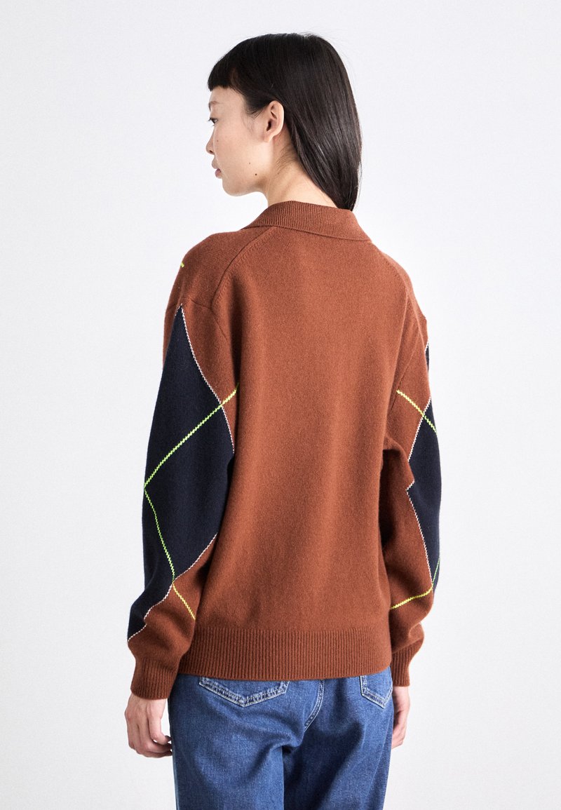Pull en laine marron avec des manches bleu foncé présentant des motifs de couture diagonaux jaunes et blancs ; ourlet et col côtelés.