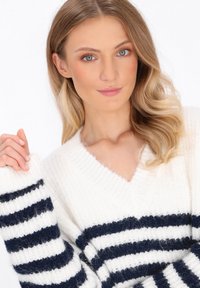 Gestreifter Pullover in Weiß und Marineblau mit V-Ausschnitt, hergestellt aus strukturiertem Strickstoff und im lockeren Schnitt, sichtbar am Oberkörper eines Models.