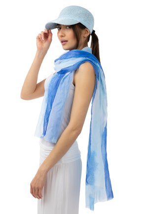 Helle blaue Mütze mit strukturierter Oberfläche, kombiniert mit einem fließenden blauen und hellblauen Schal. Beide Kleidungsstücke bestehen aus weichem, transparenter Stoff.