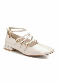 Zapato plano de charol de color beige claro con punta afilada, múltiples tiras entrecruzadas, hebillas doradas y tacón bajo cuadrado.