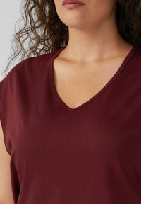 Bordeaux V-hals top van soepel stof, met korte mouwen en eenRelaxed fit, met zichtbare stiksels langs de halslijn.