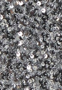 Kimaltava hopeinen paljettikangas, jossa on verkkomäinen tausta. Kangas sisältää lukuisia heijastavia pyöreitä paljetteja tiheästi aseteltuna, luoden tekstuurin pinnan.