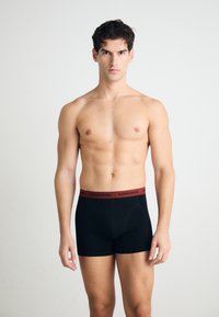 Black boxer briefs with a red "BJÖRN BORG" waistband, cotton material, fitted design, mid-thigh length, featuring a smooth texture and no patterns.