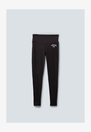 Black leggings with a high waistband, featuring stitched seams and a small white logo at the hip. Made from a smooth, stretchy material.