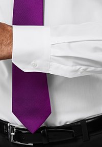 Witte overhemd met knoopmanchetten, voorzien van een gestructureerde paarse stropdas. Glad materiaal contrasteert met het patroon van de stropdas. Zwarte riem zichtbaar.