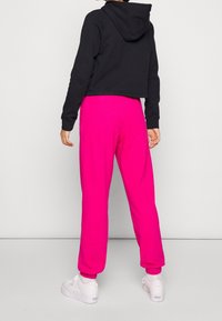 Cropped black hoodie with long sleeves paired with pink ribbed joggers. White sneakers complete the outfit.