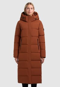 Abrigo acolchado marrón con capucha, que presenta bolsillos con cremallera, un diseño de costura vertical y una longitud larga. Textura suave y silueta moderna.