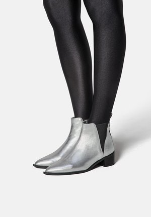 Silberne, metallische Stiefeletten mit spitzen Zehen und niedrigen Blockabsätzen. Seitliche elastische Einsätze und ein glattes Finish ergänzen das elegante Design.