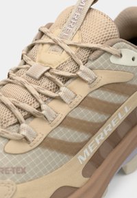 Bežne cipele za planinarenje s mrežastim panelima i teksturiranim sintetičkim materijalima. Imaju vezice, Merrell brand, te jastučić s potplatnom trakcijom.