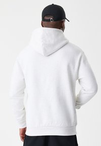 C sweatshirt cinza-claro com capuz ajustável, punhos e barra canelados. Feito de um material macio e texturizado; a vista traseira não apresenta gráficos ou padrões.