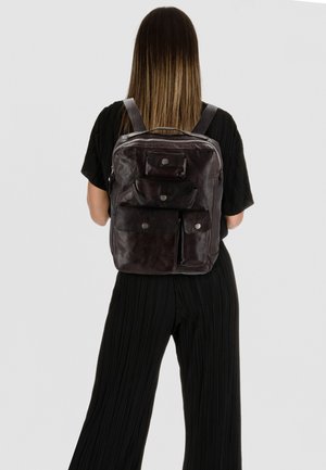Mochila de cuero marrón oscuro con múltiples bolsillos exteriores, cierre de cremallera, correas ajustables y una textura suave.
