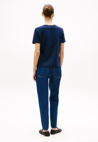Námořnické bavlněné tričko s krátkým rukávem, v kombinaci s modrými džíny s vysokým pasem. Jednoduchý design, jednobarevné provedení a volný střih.