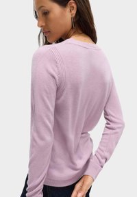 Maglione viola chiaro con maniche lunghe, polsini a costine e scollatura rotonda. Tessuto morbido e dettagli di cucitura sottili sulle spalle.