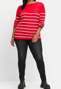 Rot-weiße gestreifte Langarmbluse mit Rundhalsausschnitt, kombiniert mit schwarzen Skinny-Jeans und schwarzen Leder-Ankle-Boots.