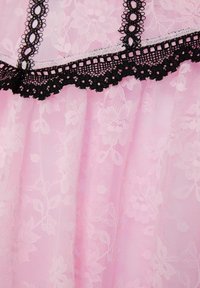 Rosa spets tyg med blommönster, accentuerat av en svart kant med vågor och intrikata spetsdetaljer längs sömmarna.