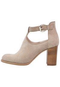 Beige mockask stövel vid vristen med rund tå, sidoutskärning och justerbar vristrem. Den har en texturerad korsettklack i trä.