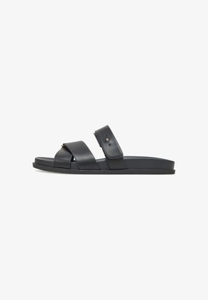 Sandalias de slide de cuero negro con dos correas anchas, plantilla acolchada y suela plana de goma con un sutil detalle de tachuelas.