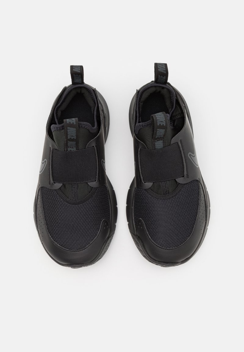 Baskets noires avec un extérieur en cuir lisse et des panneaux en mesh, dotées d'une sangle à boucle auto-agrippante pour un maintien sécurisé.