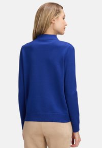 Blå tröja med hög krage, ribbade manschetter och nederkant, tillverkad av ett slätt stickat material, med en enfärgad design utan mönster.