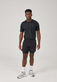 Black athletic t-shirt and matching shorts made of lightweight fabric. White sneakers with gray accents and white crew socks. Simple design.