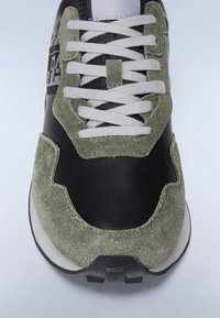 Czarne skórzane sneakersy z zielonymi zamszowymi akcentami, teksturowana powierzchnia, szare sznurowadła i wyściełany kołnierz. Guma podeszwy z bieżnikiem.