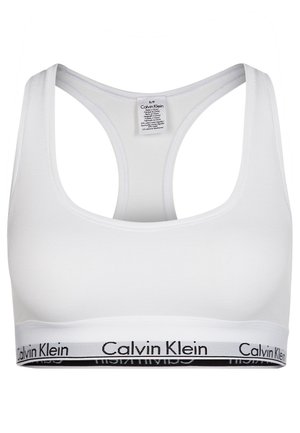 Hvit bomullsbralette med rund hals, racerback-design, og et svart logobånd nederst. Glatt tekstur, minimalistisk stil.