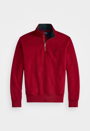 Sweat-shirt rouge avec un col zippé, présentant une doublure à carreaux sombre. Tissu doux, poignets et ourlet côtelés avec un petit logo sur la poitrine.