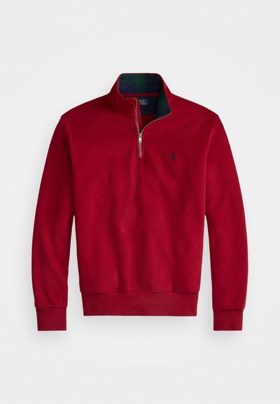 Rdeča jopica s kapuco in zadrgo, ki ima temno karo podlogo. Mehka tkanina, rebrasti manšeti in rob, z majhnim logotipom na prsih.