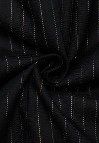 Schwarzer Stoff mit dünnen vertikalen weißen Streifen, gedreht in einer spiralförmigen Faltung, um die Textur und das Muster zu betonen.