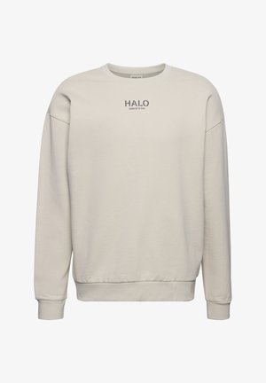 Jasno beżowy sweter z okrągłym dekoltem i długimi rękawami. Posiada małe logo "HALO" w ciemnoszarym kolorze na środku przodu. Miękka tekstura materiału.