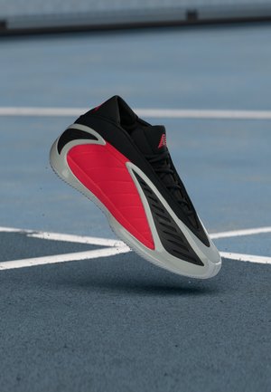 Μαύρο αθλητικό παπούτσι με κόκκινες και γκρι λεπτομέρειες, με κομψό σχεδιασμό, υφασμένα πάνελ και ελαφρύ πέλμα.