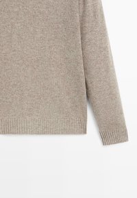 Maglione beige lavorato a maglia con polsini e orlo a coste, maniche lunghe, tessuto morbido e testurizzato, mostrato su sfondo bianco.
