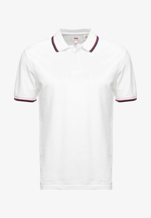 Polo blanc à manches courtes avec bordures rouges et bleu marine sur le col et les poignets, doté d’une patte de boutonnage à deux boutons et d’une étiquette Levi’s à l’intérieur du col.
