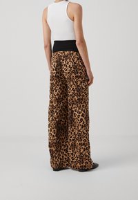 Leopardmönstrade vida byxor med svart elastisk midja, med en mjuk textur och en avslappnad passform.