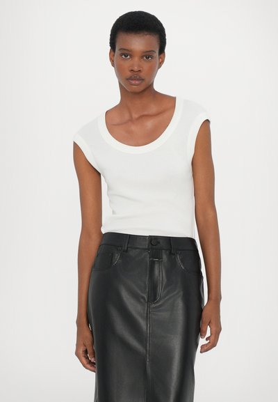 White sleeveless top with a wide round neckline, paired with a black leather pencil skirt featuring a front slit and belt loops.