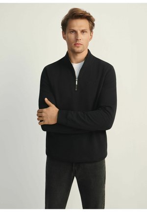 Czarny pulower z ćwierć zamkiem, wykonany z gładkiego materiału, z małym logo na piersi, długimi rękawami i luźnym krojem.