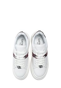 Bílé kožené tenisky mají kulatou špičku, strukturovaný burgundský akcentní pás a černý logový detail. Zapínání na šněrování s plochými tkaničkami.